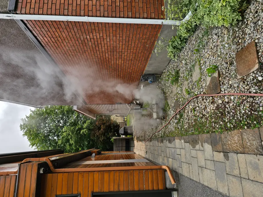Saturated steam treatment in progress on an interlock patio, steam plume rising from the pavers