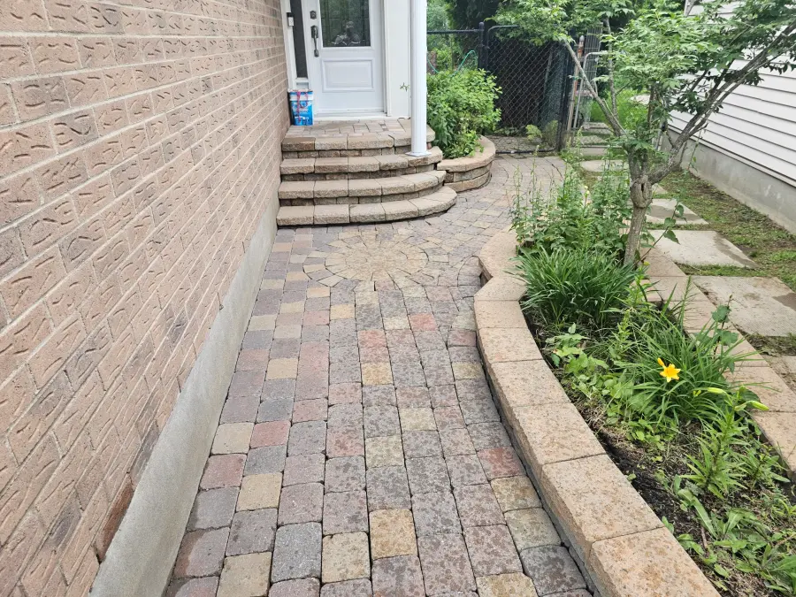 Cleaned multi-tone paver walkway beside a brick house after Natural Finish restoration