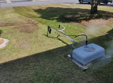 The saturated-steam weeding unit at work, steam rising over a front lawn