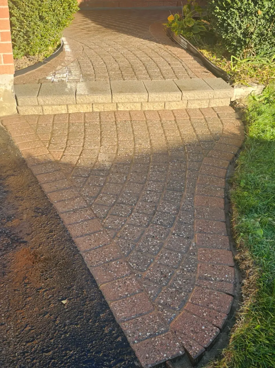 Curved red-brick walkway freshly cleaned and re-sanded — crisp natural-finish joints