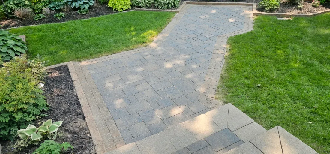 Elevated view of an S-curve walkway restored and re-sanded but unsealed — flat grey-tan pavers