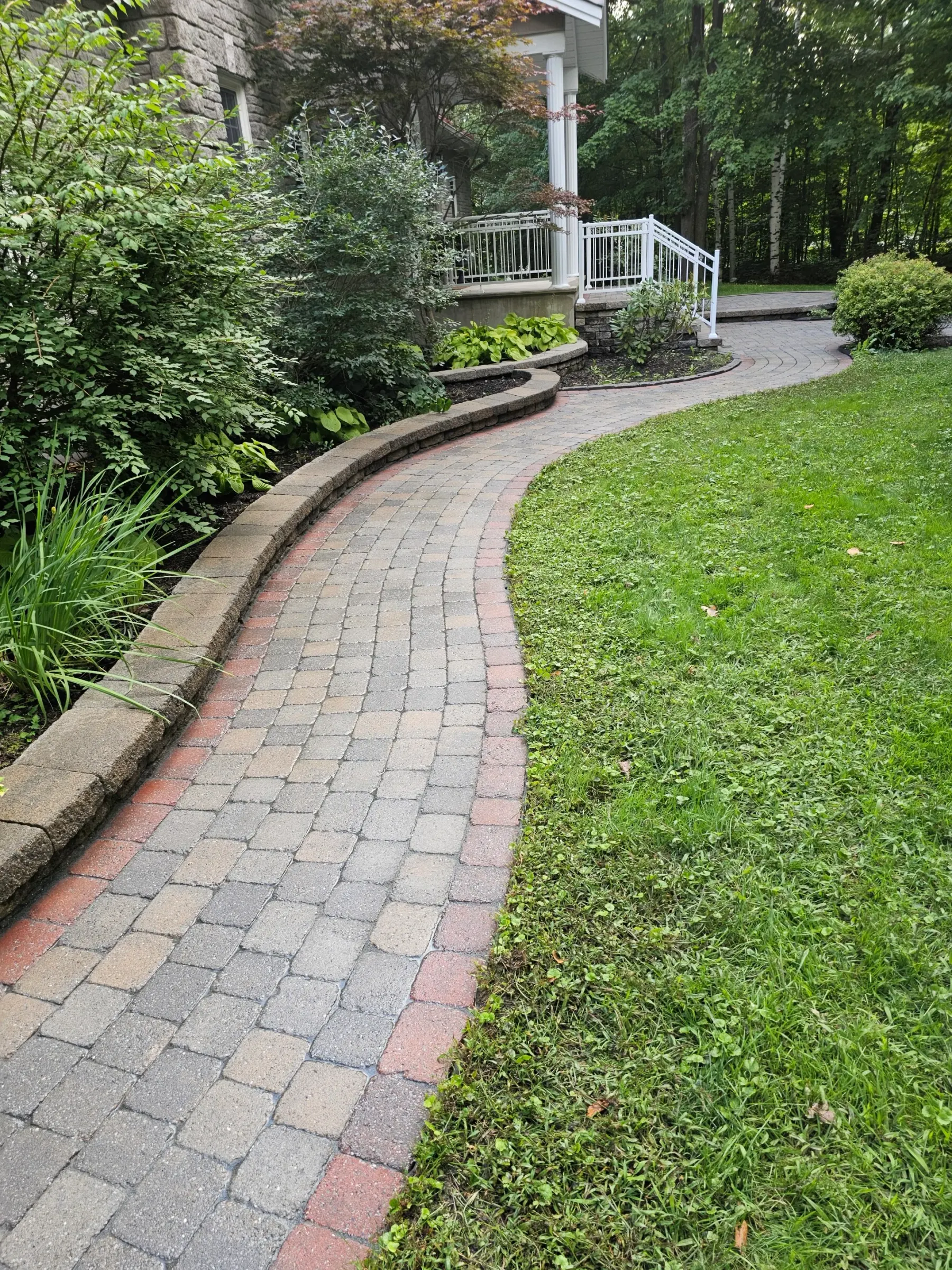 The same garden walkway restored — cleaned tumbled pavers, crisp lawn edge